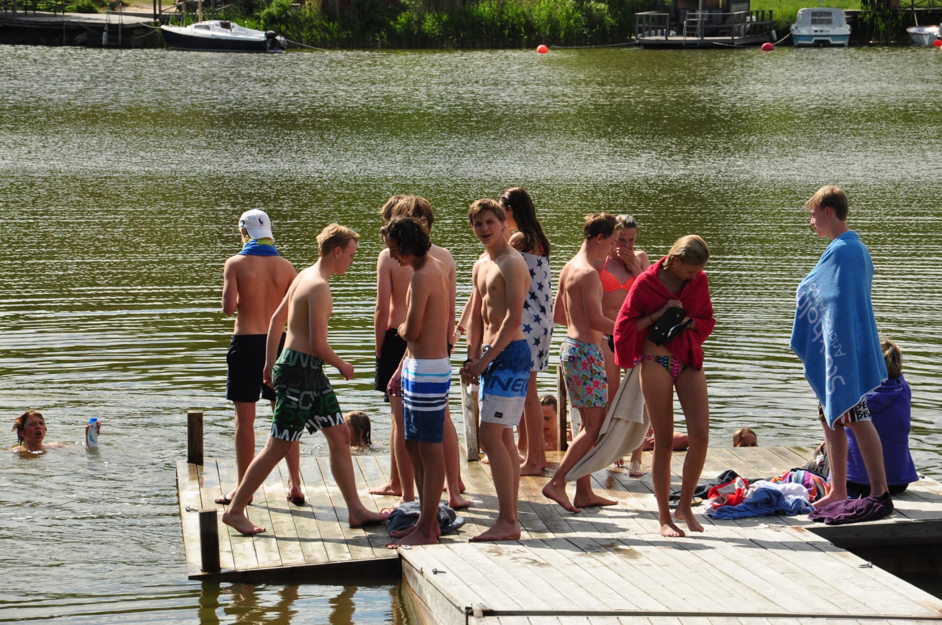 Ungdomar på bryggan vid sjön en solig sommardag